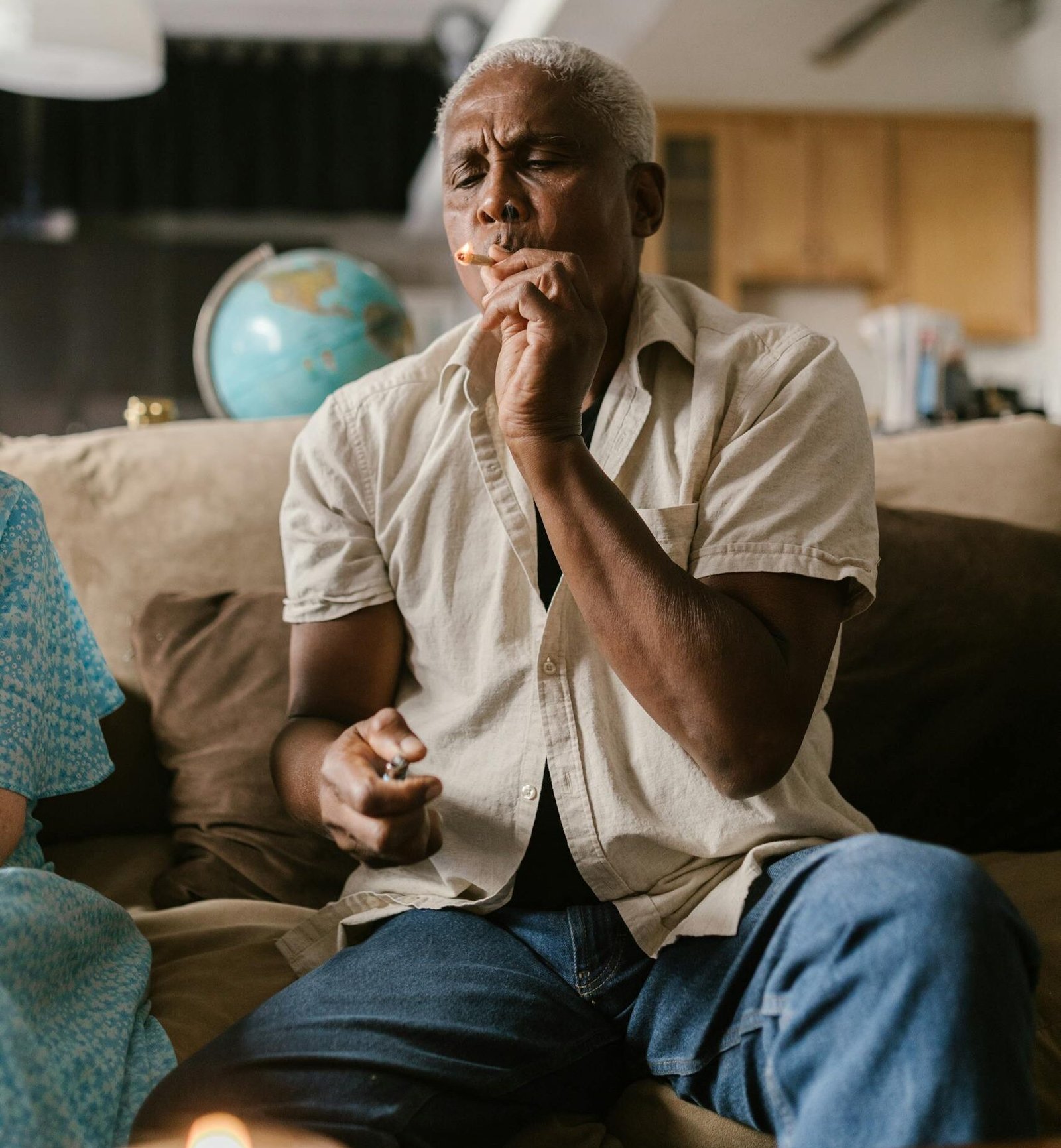 Senior man enjoying cannabis on a sofa in a living room, reflecting relaxation.